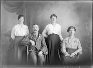 Studio portrait of members of an unidentified family, showing the man and the older woman sitting on cane seats, with the two younger women standing behind them, possibly Christchurch district