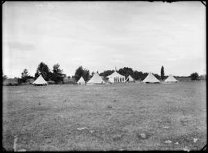Boy Scouts camp, showing seven tents and unidentified group of scouts and leaders in front of the tents, in an unidentified park, possibly Christchurch district