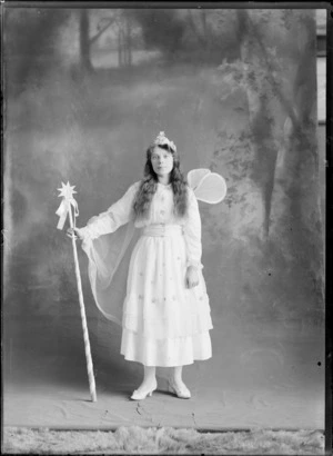 Studio portrait of an unidentified girl, dressed in a fairy costume, with a crown, fairy wings and a star staff, possibly Christchurch district