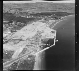 Mt Maunganui, Tauranga, Bay of Plenty, showing constructrion of wharf out into the harbour, with view inland over inlet to hills beyond