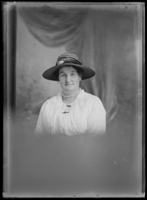 Studio upper torso portrait, unidentified older woman with pearl necklace and a large hat with a flower, Christchurch