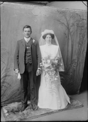 Studio unidentified wedding portrait, bride with long veil holding flowers and groom with carnation, Christchurch