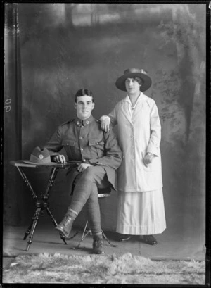 Studio portrait of Robert Hartley Goodall in uniform seated and Virtue Hannah Goodall standing with arm on his shoulder