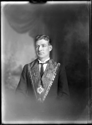 Studio upper torso portrait of an unidentified man, with v-neck tasselled sash with 'C R' and an ornate Lodge badge of the 'Ancient Order of Foresters', Christchurch