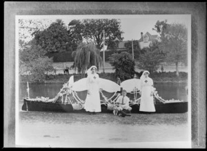 Two unidentified red cross nurses with a boy and dog, standing in front of a boat on the [Avon] River, probably Christchurch district