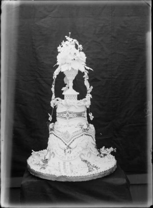 Decorated wedding cake with words 'Golden wedding 1866-1916' on the front and flowers on the top