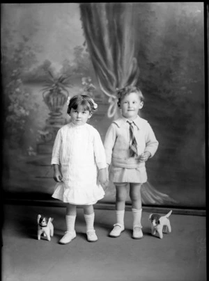 Studio portrait of unidentified girl and boy, with toy dogs, probably Christchurch