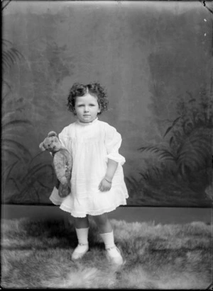 Studio portrait of unidentified girl, holding a teddy bear, probably Christchurch district