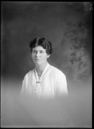 Studio upper torso portrait of unidentified young woman with round ball necklace and three NZ stamps brooch, Christchurch