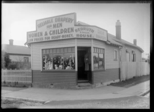 Exterior view of a corner-store drapery, Redruth House, proprieter H Spiller, with signage on front, reading 'Reliable Drapery For Men, Women & Children, Low Prices For Ready-Money', possibly Christchurch district