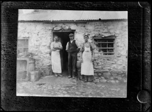 Group of three unidentified men outside a stone building, shows two men wearing aprons and one man smoking a pipe, probably Christchurch district