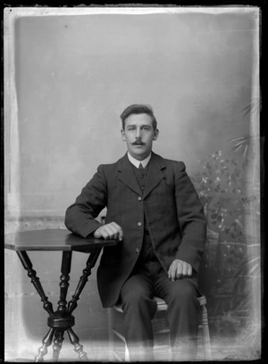 Studio portrait of unidentified man, sitting at a table, probably Christchurch district