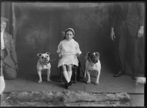 Studio portrait of unidentified small girl, with two British bulldogs, includes two unidentified obscured men, probably Christchurch district