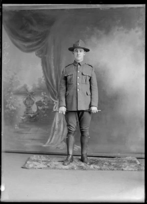 Studio portrait of unidentified soldier, in uniform, holding a swagger stick, probably Christchurch district