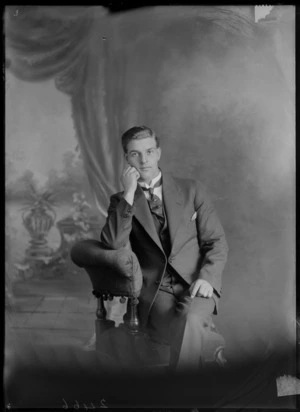 Studio unidentified portrait of a young man in a pinstriped suit, butterfly shirt collar and patterned tie with tie pin sitting in a chair, Christchurch