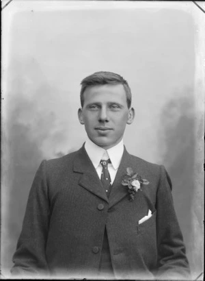 Studio upper torso wedding portrait of unidentified young groom with double round shirt collar and polka dot tie with horse shoe jewelled tie pin and buttonhole, Christchurch