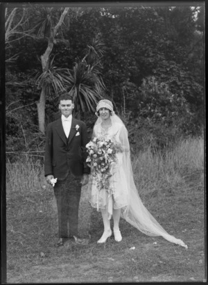 Wedding portrait, showing an unidentified bride and groom standing in an unidentified outdoor location, including cabbage tree, possibly Christchurch district