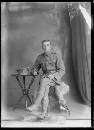 Studio portrait of an unidentified man wearing a military uniform, seated, holding a baton, possibly Christchurch district