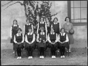 Hastings High School 2nd IX girls basketball team with cups, in front of building, Hawke's Bay District