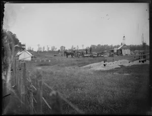 Timber mill, view of mill workers with horse and cart and towing equipment with tree trunk in a field, with stacked timber and saw mill, piles of sawdust foreground, [Hastings?], Hawke's Bay District