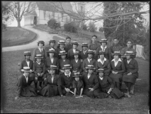 Group of Hukarere Girls and Te Aute College students in school uniforms on lawn with Te Aute College chapel on top of hill beyond, Waipawa, Hawke's Bay