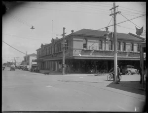 Street corner photo of Market Street, Hastings, showing large building with shops, people and cars, Hawke's Bay District