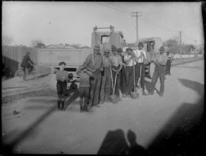 Road construction showing men with shovels and trucks, with two young boys looking on, Hawke's Bay District