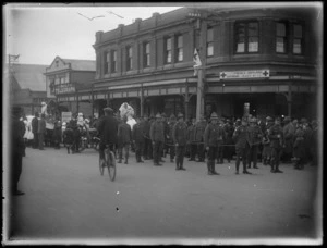 Soldiers on parade towing a field cannon [Howitzer], nursing core behind, people looking on in front of the Daily Telegraph building, Hawke's Bay District