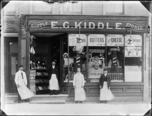 Four men standing in front of the business premises of E G Kiddle Supply Store, probably England