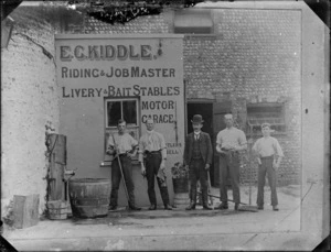 Five men standing in front of the business premises of E G Kiddle, Riding and Jobmaster, Livery and Bait Stables, England