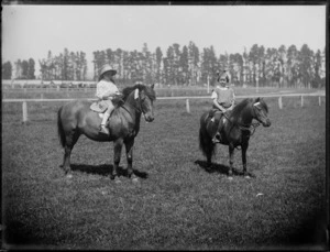 Two unidentified girls on their ponies at a track, location unidentified