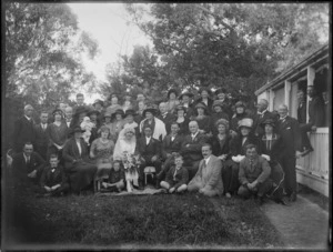 A wedding portrait of the bridegroom and bride with family members, taken in the garden, location unidentified