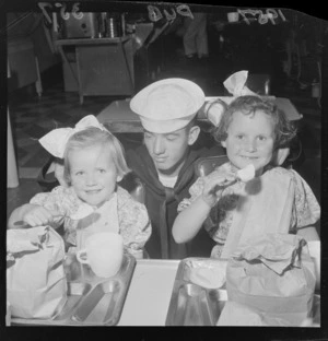 Unidentified children from the Salvation Army Orphanage, with a member of the United States Navy, on board the ship USS Cimarron