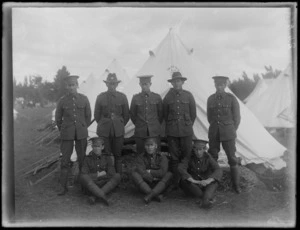 A group of unidentified soldiers standing in front of a tent, at casual camp, Hastings