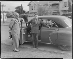 Two unidentified men [Mr Ebbett?] standing next to car, Hamilton