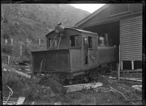 Albert Percy Godber standing in the cab of Wd class steam locomotive (NZR number 318) which has crashed through the wall of a railway shed