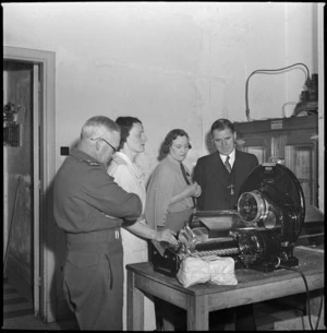 New Zealand Minister of Defence, Hon Frederick Jones, watches bread cutting machine at NZ Forces Club, Cairo - Photograph taken by S Wemyss