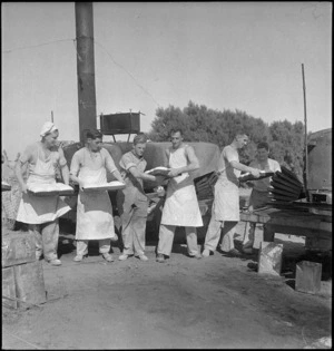 Members of NZ Field Bakery placing dough into oven in Tripolitania, Libya - Photograph taken by H Paton
