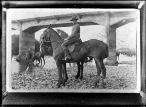 Unidentified WWI soldier on horseback [Mounted Rifles?], with another man on hoseback in the river behind, location unknown
