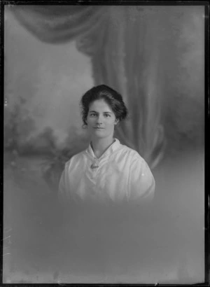 Studio upper torso portrait of an unidentified woman wearing a a white cotton blouse, showing a brooch on the front of her blouse, with a gem stone necklace, possibly Christchurch district