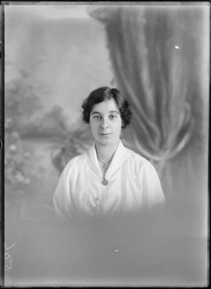 Studio upper torso portrait of an unidentified woman wearing a [nurses uniform?], with a necklace, an unidentified brooch attached to the neckline of her blouse, possibly Christchurch district