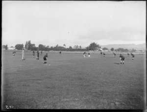 Hastings High School students playing a game of cricket on the school field, with a staff member refereeing them, Hawkes Bay District