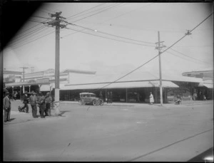 Men fixing an electric wire on the corner of Heretaunga Street, Hastings, with Land and Heighway Saddlers in the background
