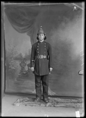 Studio portrait of unidentified fireman, in uniform, probably Christchurch district