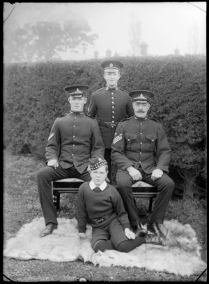 Group of unidentified men and boys, probably family members, all wearing military uniforms, including a young boy dressed in the uniform of a Public School cadet