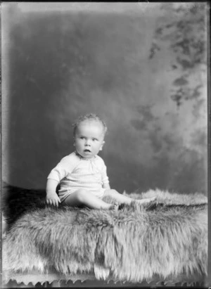 Studio unidentified family portrait of a baby sitting on fur rug, Christchurch