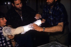 Bob Rae and George Poppleton putting plaster on Bill Hare's damaged wrist