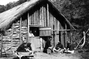 Group of unidentified Maori outside a whare at Parihaka Pa