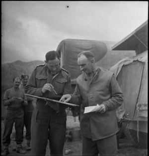 Brigadier Weir studies report handed him by Captain Sidey during initial action in Italy, World War II - Photograph taken by George Kaye