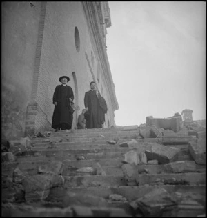Two priests stand among the rubble outside their church in Atessa, Italy, World War II - Photograph taken by George Kaye